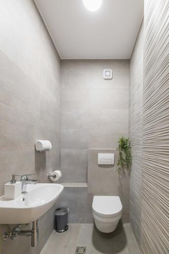 a white bathroom with a sink and a toilet at Bianca Apartment with free parking in Novi Sad