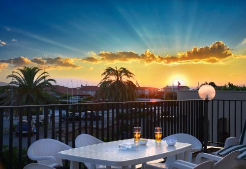 a table with two glasses on a balcony with a sunset at Hotel Paris in Lido di Camaiore