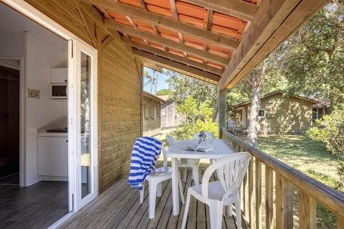 a patio with a table and chairs on a deck at Village Vacances La Forêt des Landes in Labenne