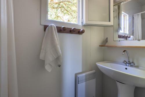 een witte badkamer met een wastafel en een spiegel bij Village Vacances La Forêt des Landes in Tarnos