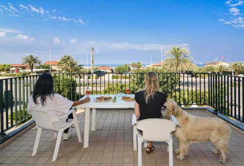 two women sitting at a table with a dog on a balcony at Hotel Paris in Lido di Camaiore
