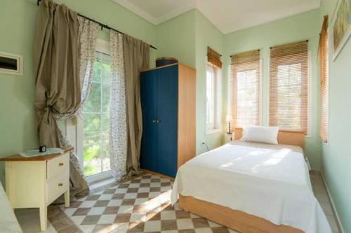 a bedroom with a white bed and a checkered floor at Home Katerina in Kýmina