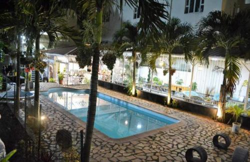 a swimming pool with palm trees in a hotel at Euro Vacances Guest House in Roches Brunes