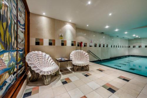 a swimming pool with two chairs and a table in a room at Courthouse Hotel London in London