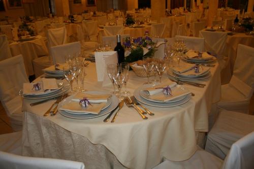a white table with plates and silverware on it at Hotel Villaggio Ristorante Pizzeria Museo TANIT in Carbonia
