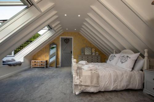 um quarto com uma cama branca num sótão em Host & Stay - Millfield Cottage em Chop Gate