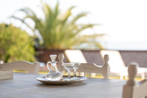 a table with a plate with two glasses on it at Villa Cortesia Maritima - seaside & private in Amarynthos