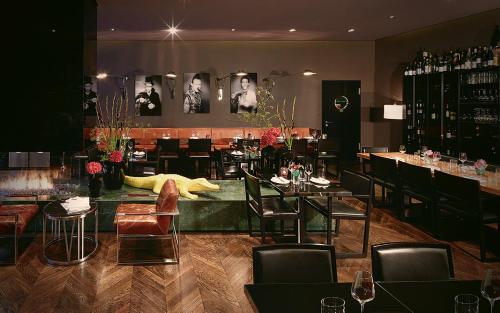 ein Restaurant mit Tischen und Stühlen und eine Bar in der Unterkunft Hotel MANI by AMANO in Berlin