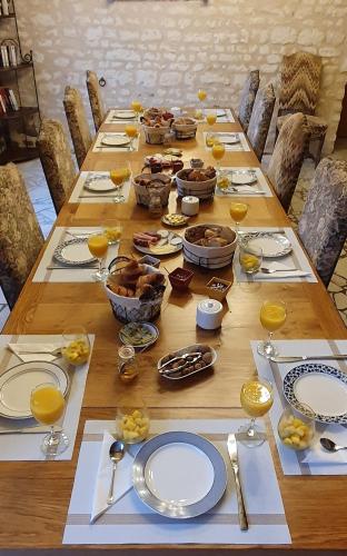 une longue table en bois avec des assiettes et des verres de jus d'orange dans l'établissement La Ferme de Couffy, à Couffy