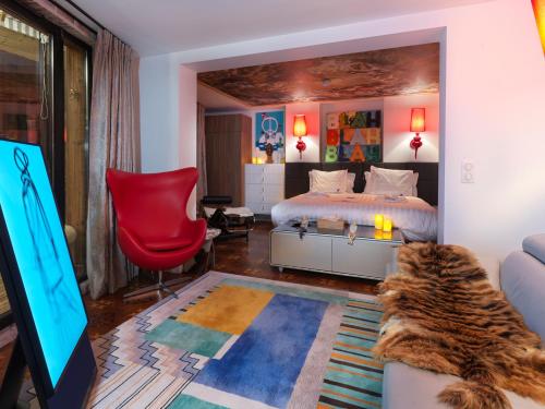 a bedroom with a bed and a tv and a red chair at Snow Lodge Hotel Courchevel 1850 in Courchevel