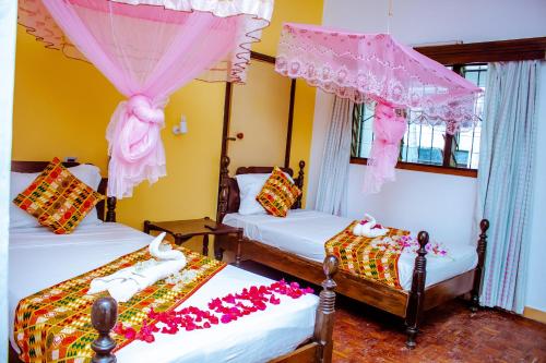 Habitación con 3 camas con flores. en Papillon Garden Bar Villas, en Bamburi