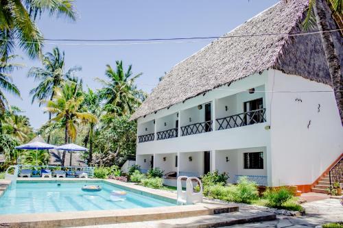 a villa with a swimming pool and a building at Papillon Garden Bar Villas in Bamburi