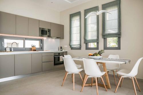 a kitchen with a table and white chairs in it at Villa Sorian Kokkino in Vlachata