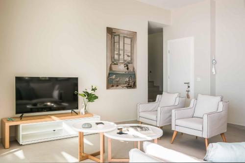 a living room with a tv and two chairs and a table at Villa Sorian Kokkino in Vlachata
