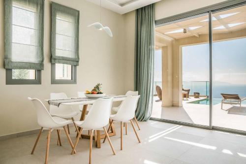 a dining room with a table and white chairs at Villa Sorian Kokkino in Vlachata