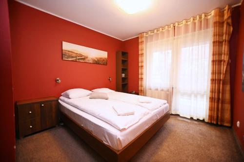 Un dormitorio con una cama con paredes rojas y una ventana en Victus Apartamenty, Apartament Sopot, en Sopot