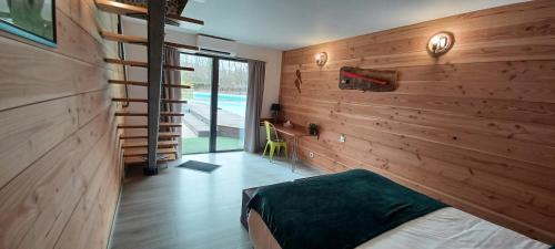 Un dormitorio con una pared de madera y una cama. en Au Petit Pressoir B&B, en Givry