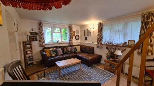 sala de estar con sofá de cuero y mesa en The Cabin, Litlington - Dogs Welcome! en Litlington
