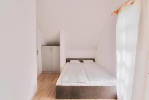 Habitación blanca pequeña con cama. en Villa Oliver Balatonlelle, en Balatonlelle