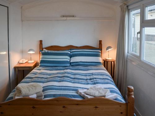 een slaapkamer met een bed met blauwe en witte strepen bij Thalassa in Pagham