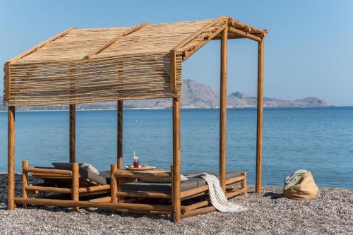 a wooden gazebo with chairs and a table on a beach at Lindos Aqua Terra in Líndos