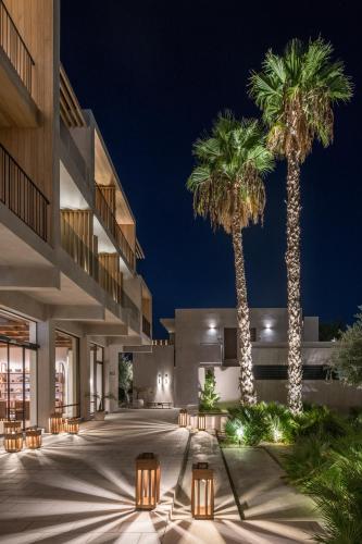 a courtyard with two palm trees and a building at Lindos Aqua Terra in Líndos