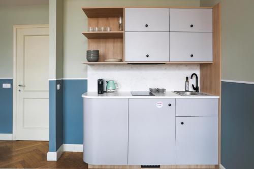 a kitchen with white cabinets and a sink at Numa Prague Flow in Prague