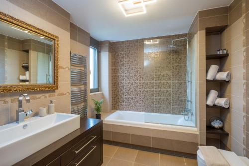 a bathroom with a tub and a sink and a mirror at Villa Merlin in Galatás