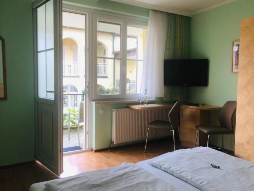 a bedroom with a bed and a desk and a television at Pension Peterhof in Mörbisch am See