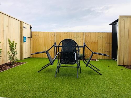 a chair sitting on the grass in a backyard at Arena,Railway Station Townhouse with Free car park in Christchurch
