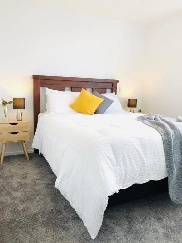 a bedroom with a large white bed with a yellow pillow at Arena,Railway Station Townhouse with Free car park in Christchurch