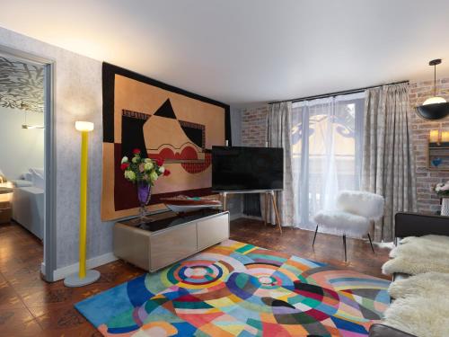a living room with a television and a colorful rug at Snow Lodge Hotel Courchevel 1850 in Courchevel