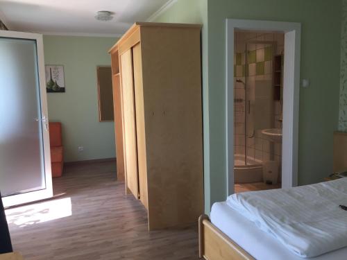 a bedroom with a bed and a bathroom with a shower at Pension Peterhof in Mörbisch am See