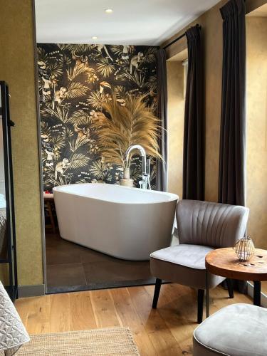 a bathroom with a white tub and a plant wall at Bed and Breakfast Geliefd in Voorhout