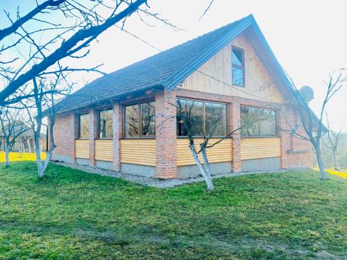 a small house with windows on a grass field at Vikend na Ozrenu in Bosansko Petrovo Selo