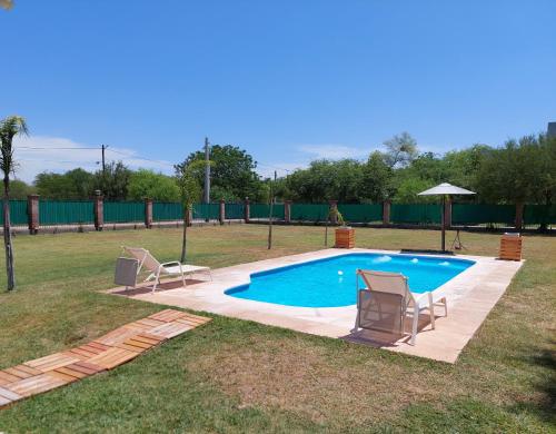 - une piscine avec 2 chaises et un parasol dans l'établissement Finca La Candelaria, à Santiago del Estero