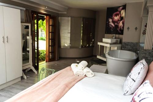 - une chambre avec une baignoire et un lit avec des serviettes dans l'établissement Sewende Hemel, à Kroonstad