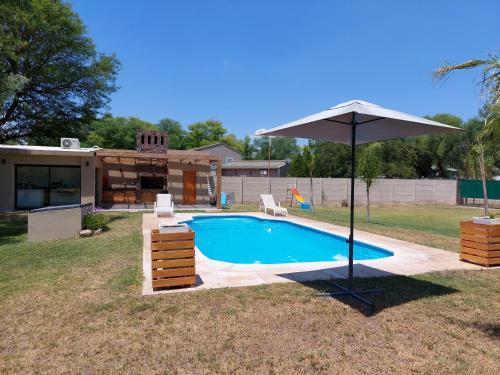 una piscina con sombrilla junto a una casa en Finca La Candelaria en Santiago del Estero