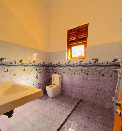 a bathroom with a toilet and a window and a sink at Golden Town Hotel in Tangalle