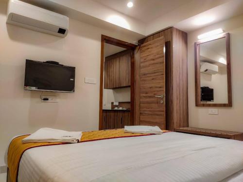 a bedroom with a large bed with a tv on the wall at RR Mount Elite Suites in Chennai