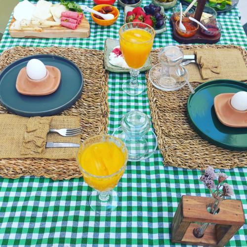a green and white table with plates and glasses of orange juice at Zarbalı Cunda in Ayvalık
