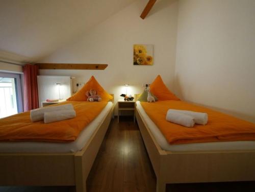 two beds in a room with orange sheets at Ferienwohnung 6 in Ochsenhausen