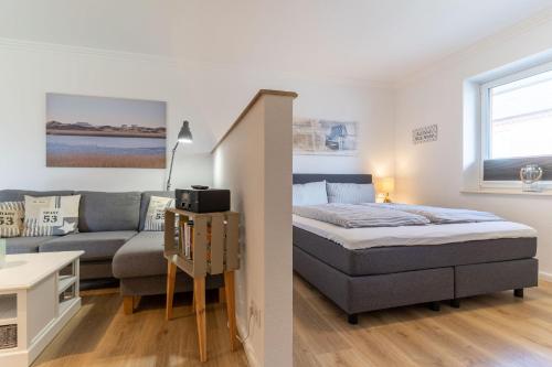 1 dormitorio y sala de estar con 1 cama y 1 sofá en Deichlamm en Sankt Peter-Ording
