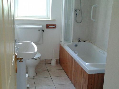 een badkamer met een toilet, een bad en een wastafel bij Betty's Cottage in Ardea