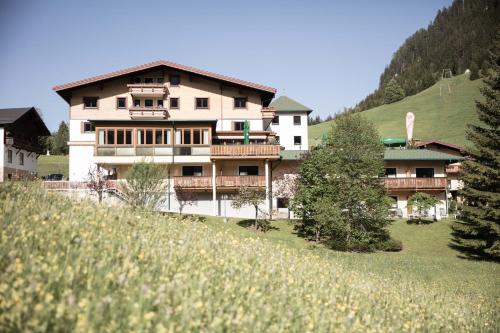 ein großes Gebäude auf einem Hügel mit Bäumen davor in der Unterkunft Hotel Rotlechhof in Berwang