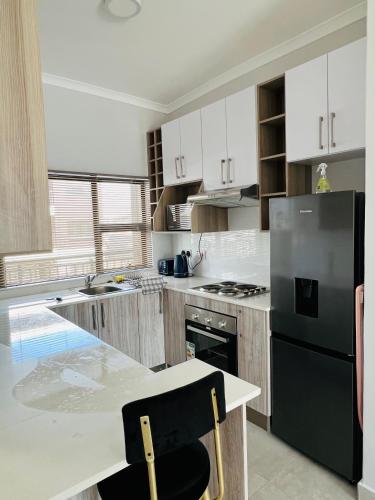 a kitchen with a black refrigerator and a table at Zanaya Apartments in Gaborone