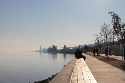 a person sitting on a bench next to a body of water at Suites & Apartments DP VFXira in Vila Franca de Xira