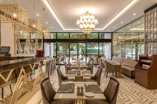 イスタンブールにあるRamada by Wyndham Istanbul Golden Hornのテーブルと椅子、シャンデリアのあるレストラン