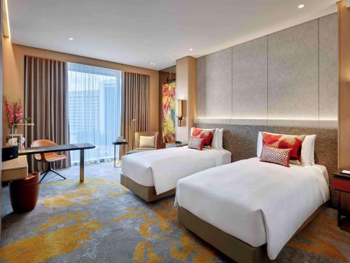 a hotel room with two beds and a desk at Sofitel Singapore City Centre in Singapore