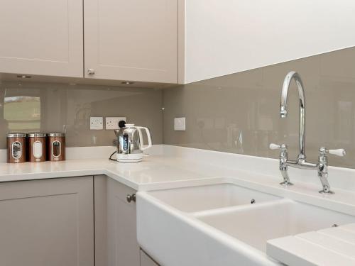 a white kitchen with two sinks and two faucets at The Hideaway -ukc3844 in Ticknall